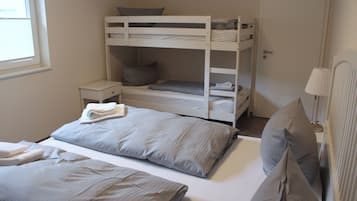 Une chambre avec un lit superposé, une petite table de chevet, une lampe et une fenêtre.