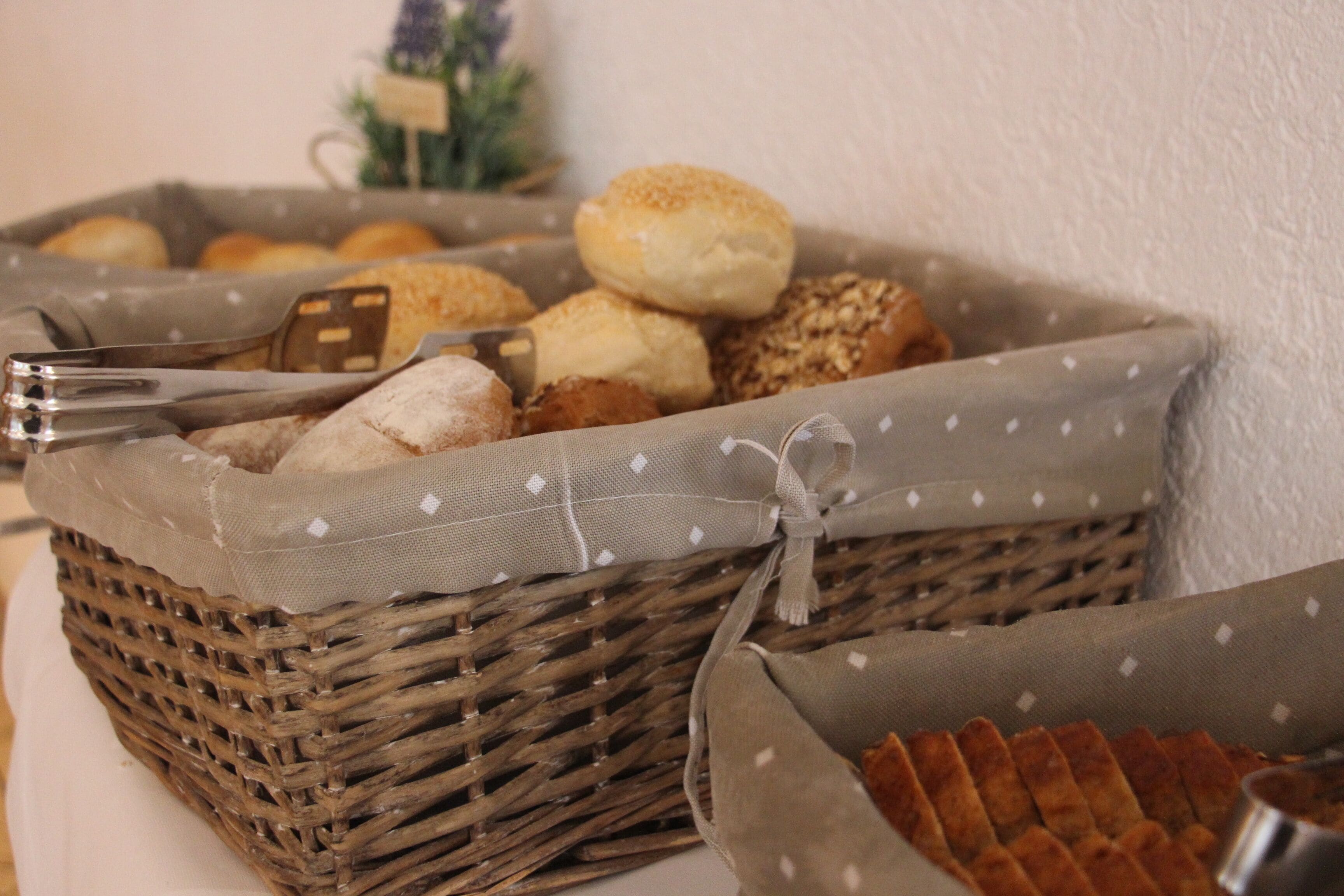 Un panier en osier rempli de diverses sortes de produits de boulangerie, notamment du pain et des pâtisseries.