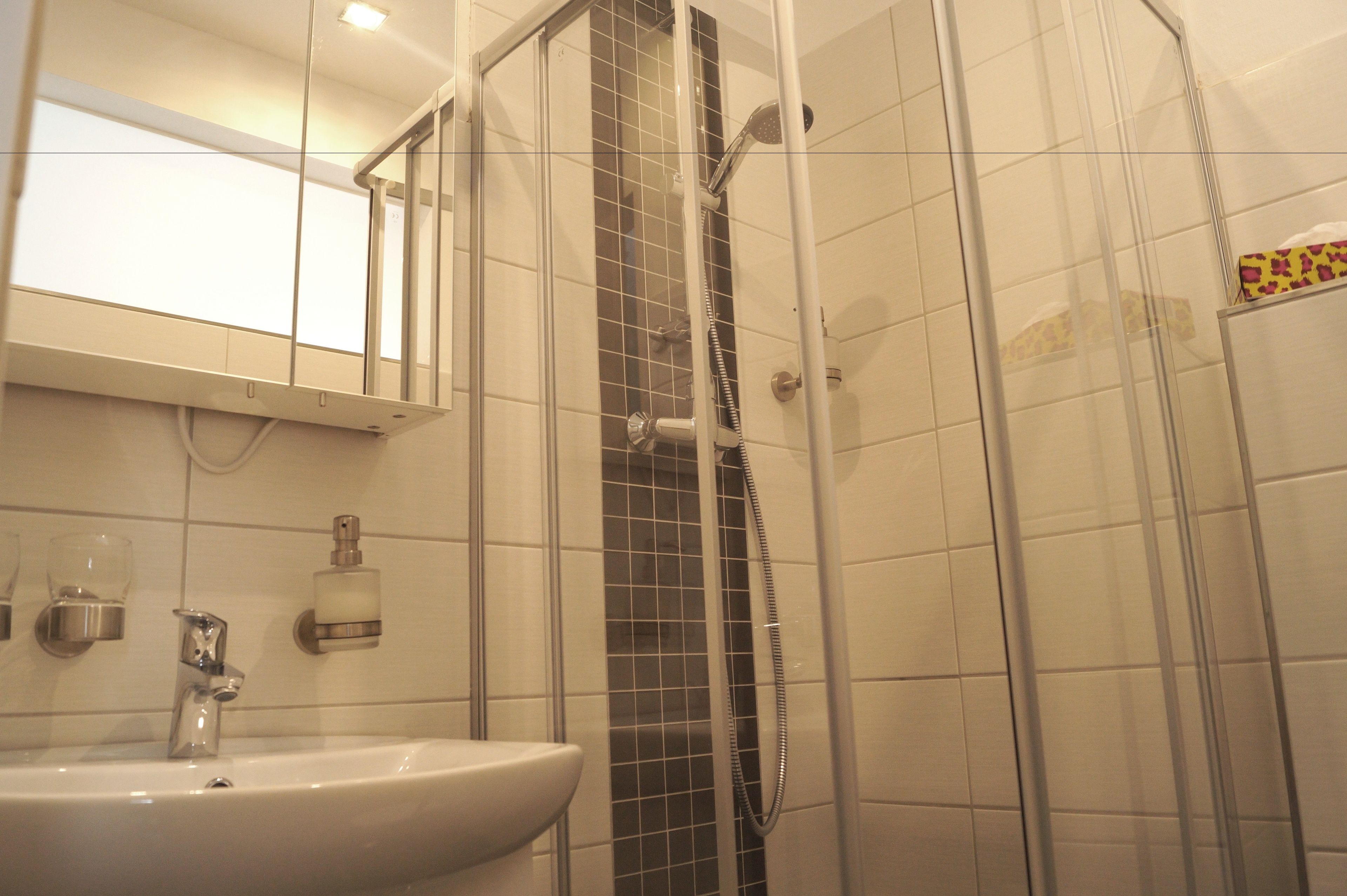 Ein Badezimmer mit einem weißen Waschbecken, einem Spiegel und einer Duschkabine.