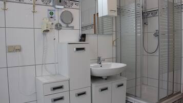 A bathroom with a white sink, a mirror, a shower enclosure, and a telephone.