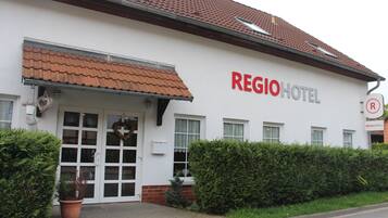 Regio Hotel features a white facade, red-tiled roof, and a prominent entrance with glass panels.