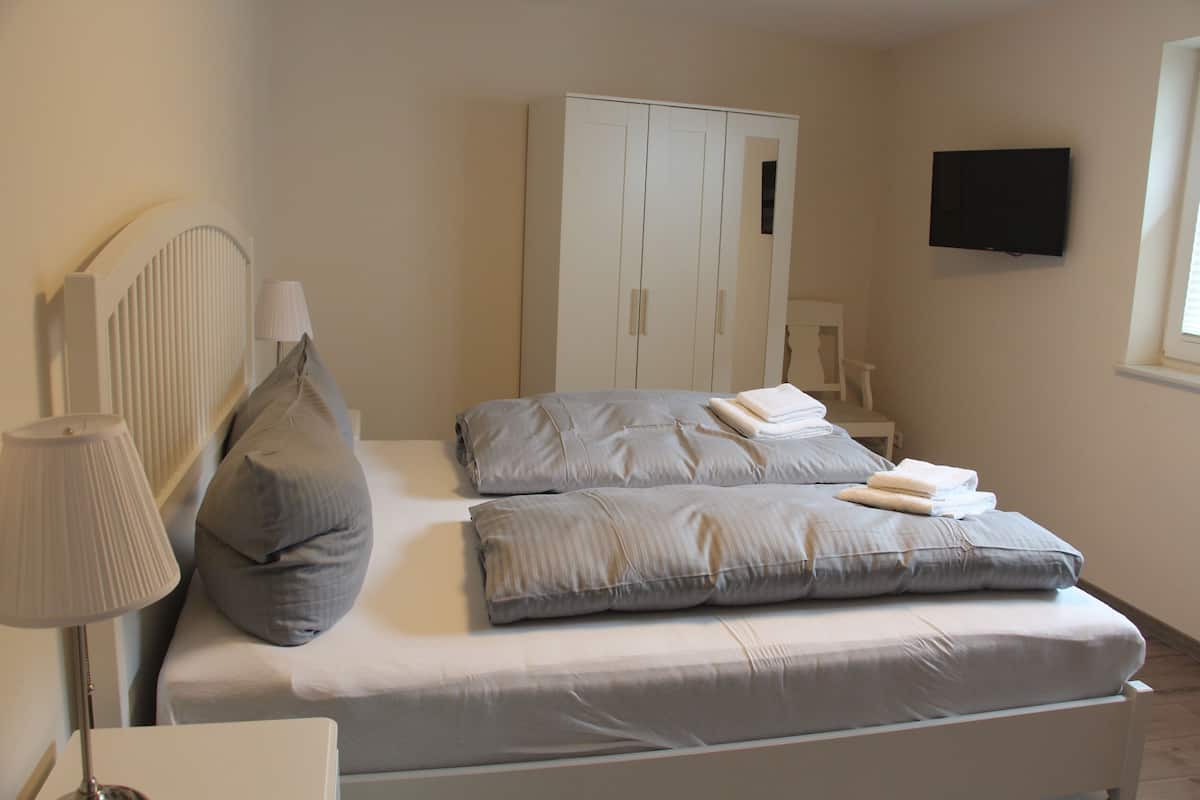 A bedroom with a bed, a wardrobe, a TV, and a bedside table.