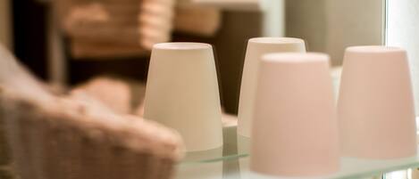 Une étagère en verre sur laquelle reposent trois objets cylindriques blancs, qui pourraient être des récipients à savon ou à lotion, dans une salle de bain.