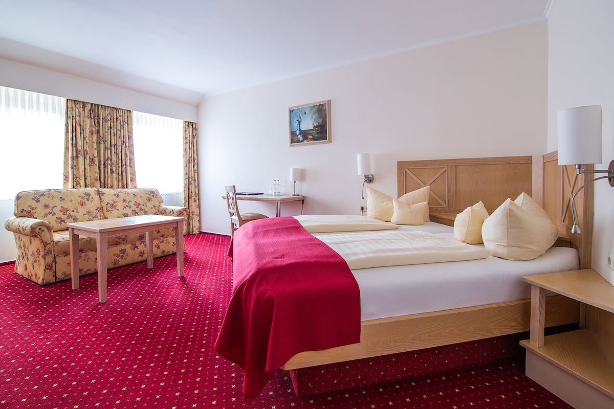 A hotel room with a bed, a sofa, a desk, and a chair.