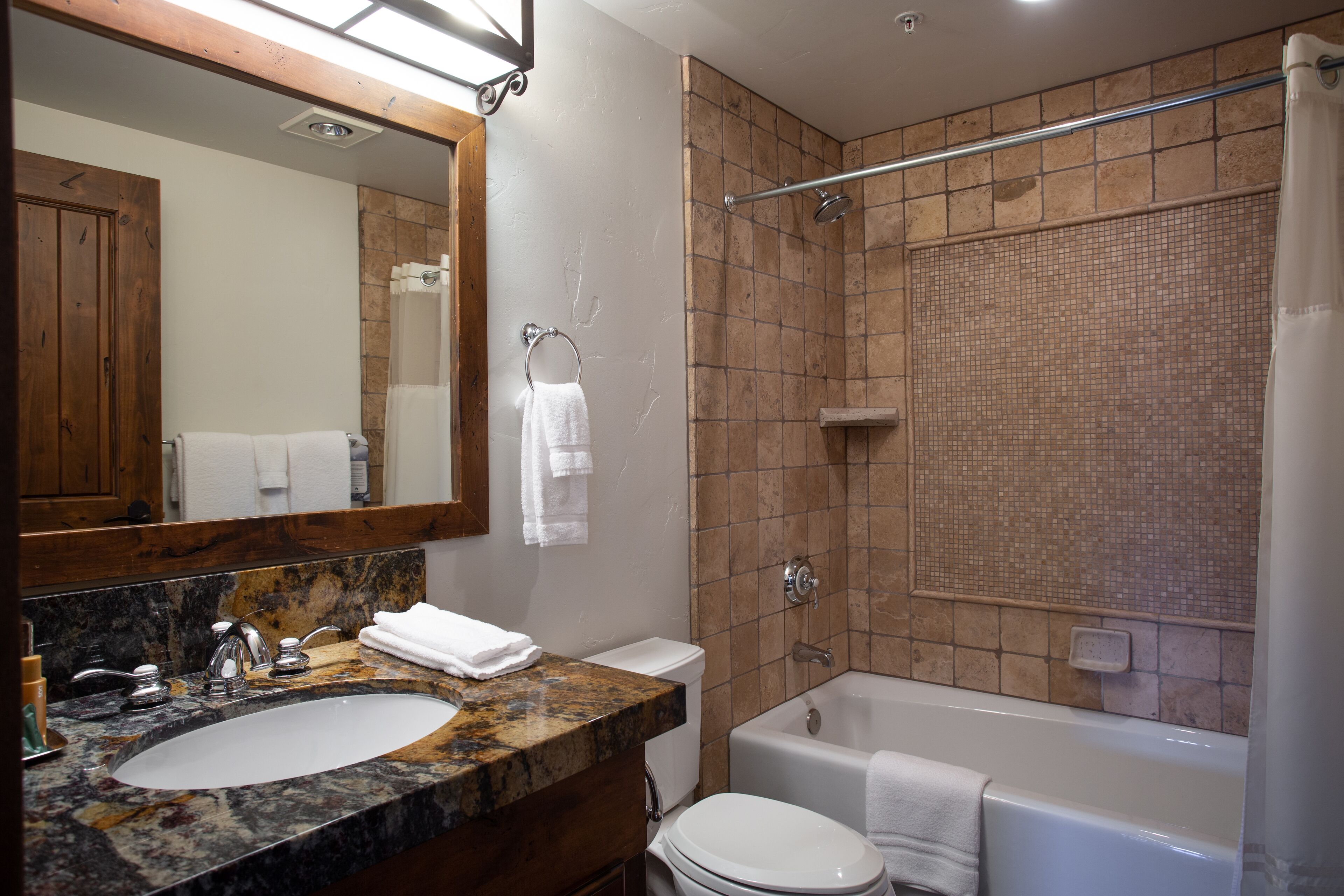 Un baño con lavamanos de mármol, inodoro, bañera y ducha con puerta de cristal.