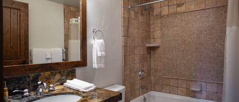 Un baño con lavamanos de mármol, inodoro, bañera y ducha con puerta de cristal.