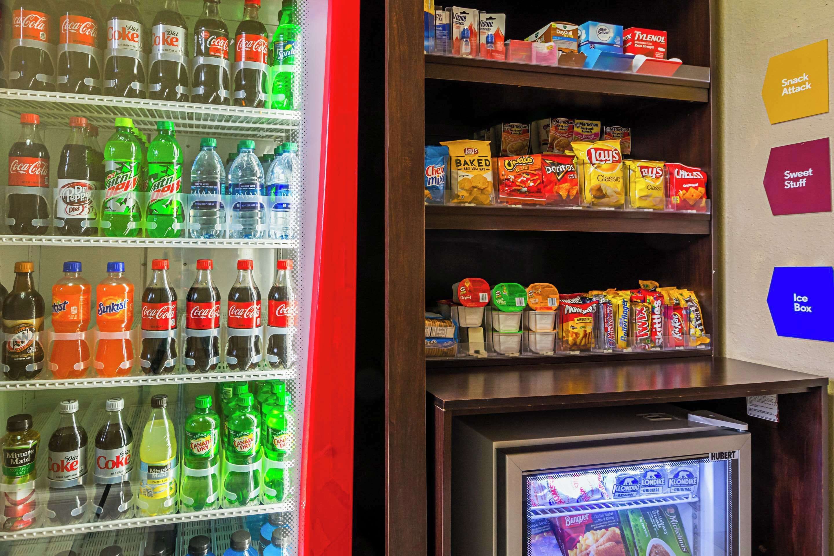 Máquina expendedora llena de diversos aperitivos y bebidas, incluyendo refrescos y papas fritas.