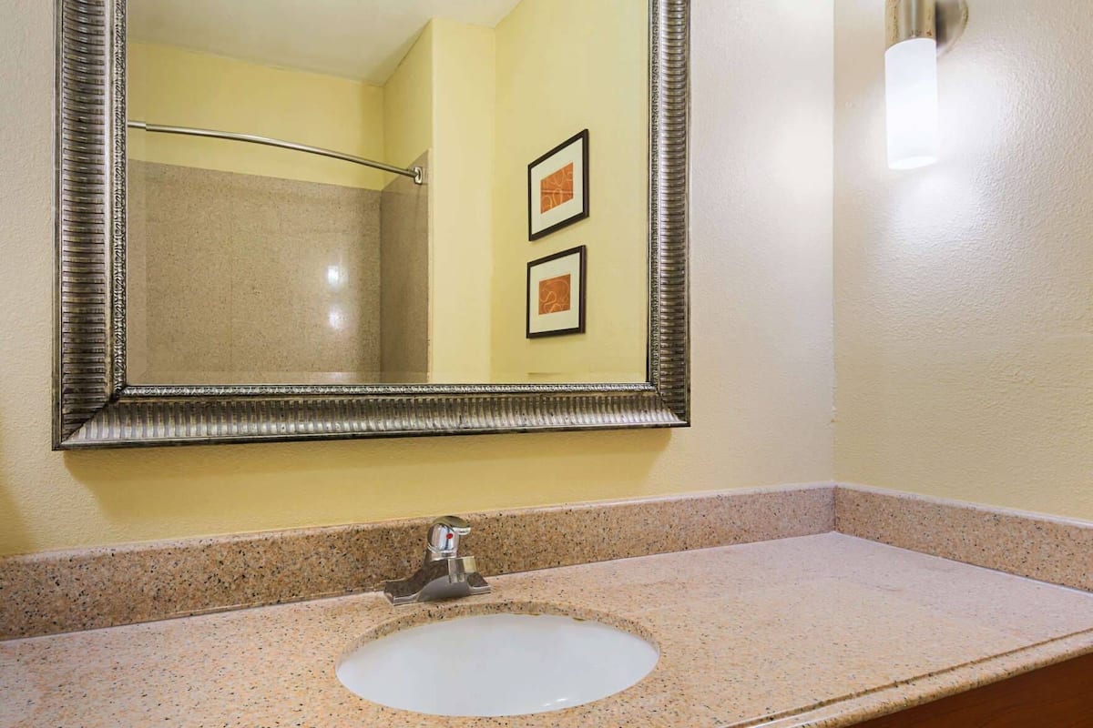 A bathroom with a granite countertop, a sink, a mirror, and a towel rack.