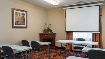 A conference room with a projector screen, a fireplace, and a patterned carpet.