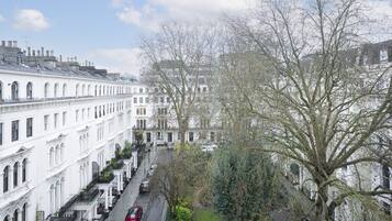 A row of white buildings with arched windows and a tree in the foreground.