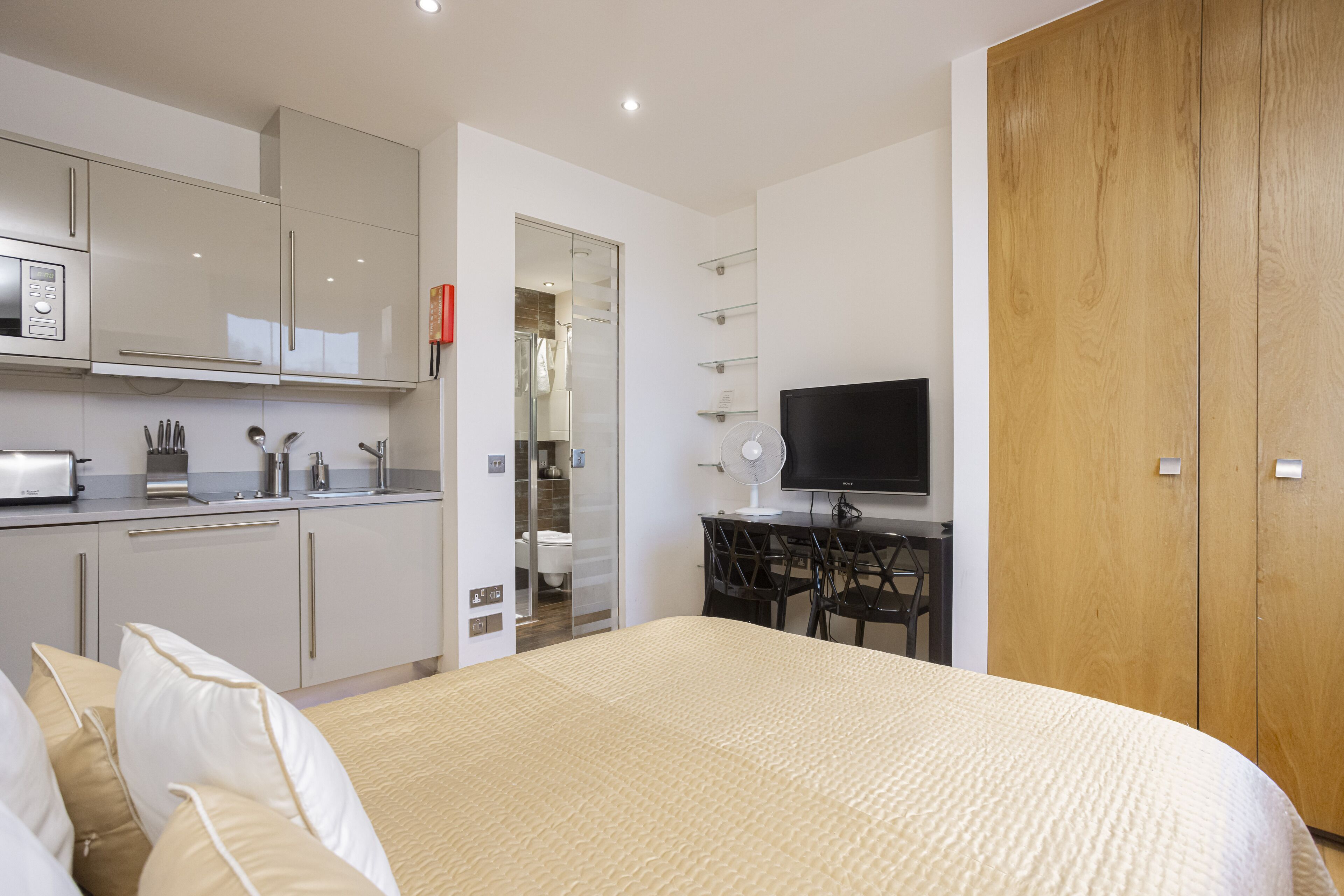 A modern hotel room with a bed, a TV, a desk, and a wardrobe.