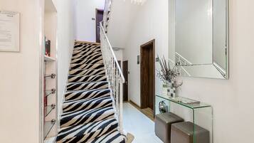 A staircase with zebra-striped carpet, a glass console table with decorative items, and a large mirror on the wall.