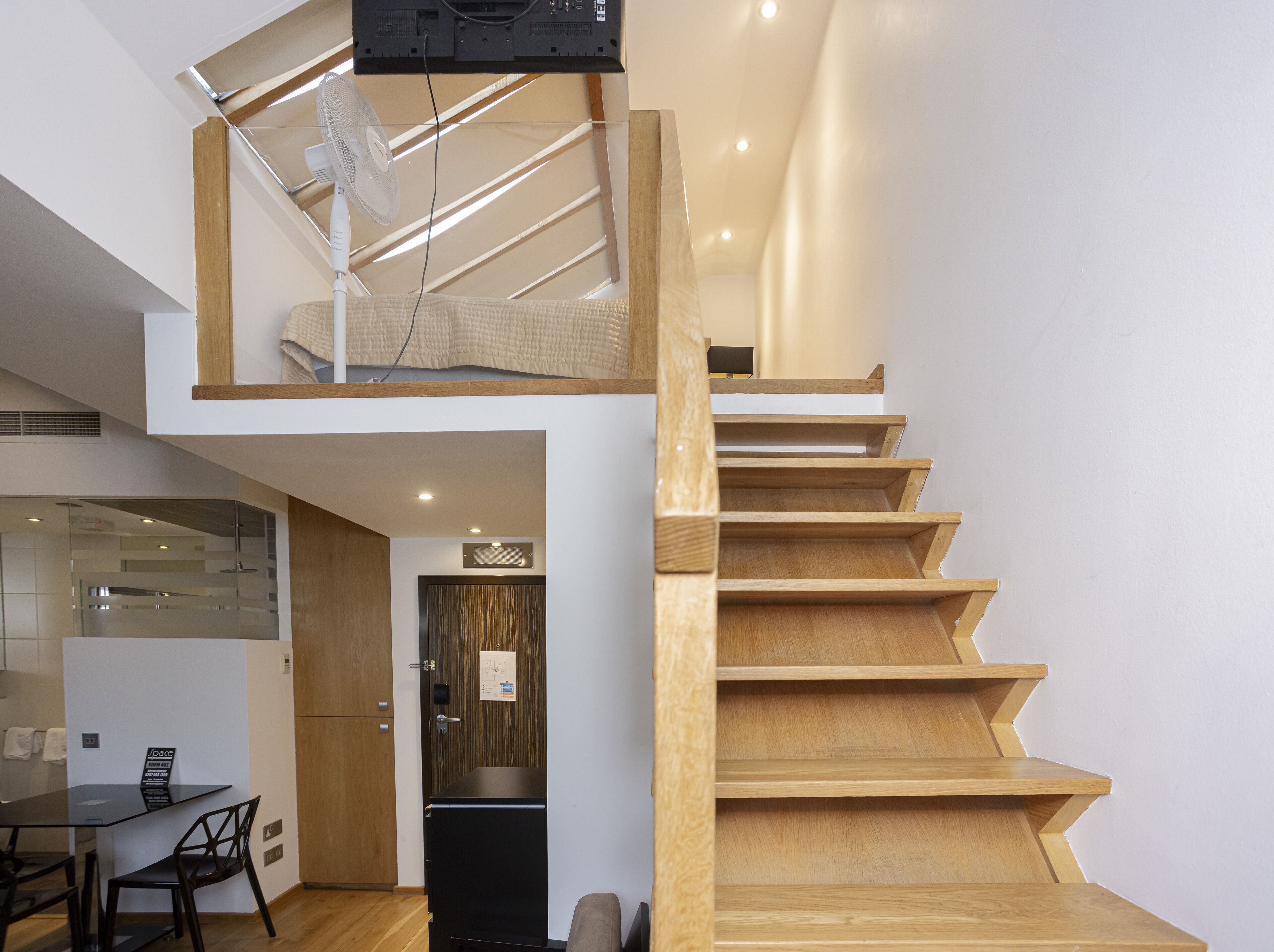 A modern interior with a wooden staircase, a dining area, and a kitchen.