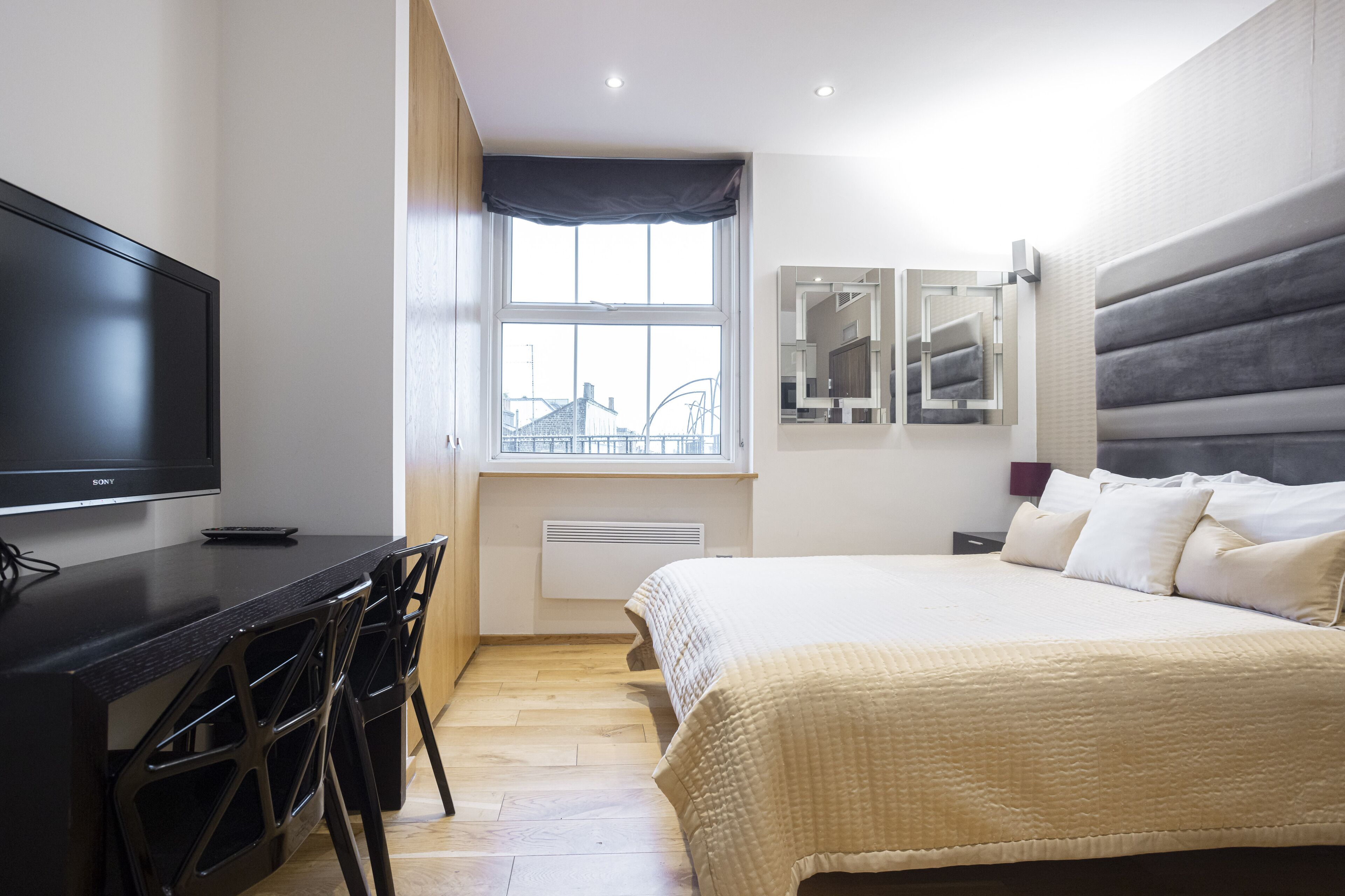 A modern bedroom with a bed, a desk, and a television.