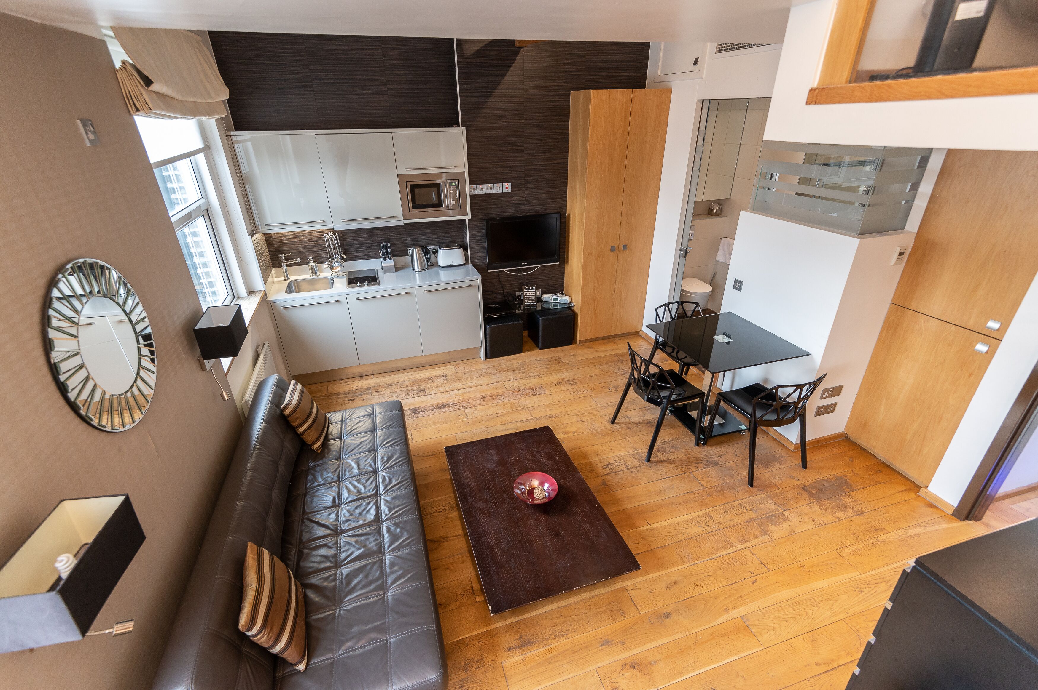 Un espace de vie compact comprenant un coin cuisine, un coin repas et un coin salon.