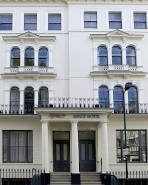 A white building with a central entrance, double doors, and a balcony with a railing. - Space Apart Hotel (London)