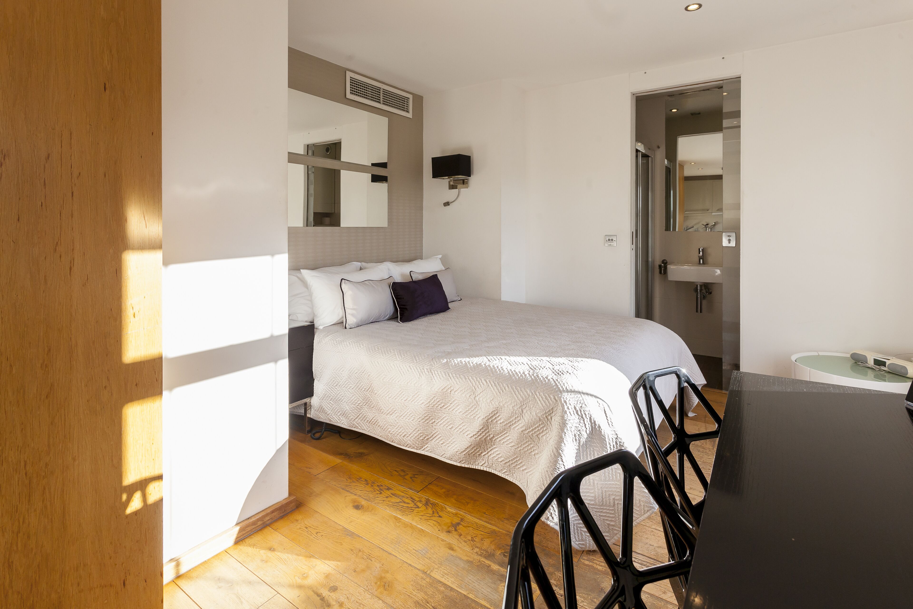 Une chambre à coucher comprenant un lit, une table de chevet et une salle de bain avec un lavabo et un miroir.