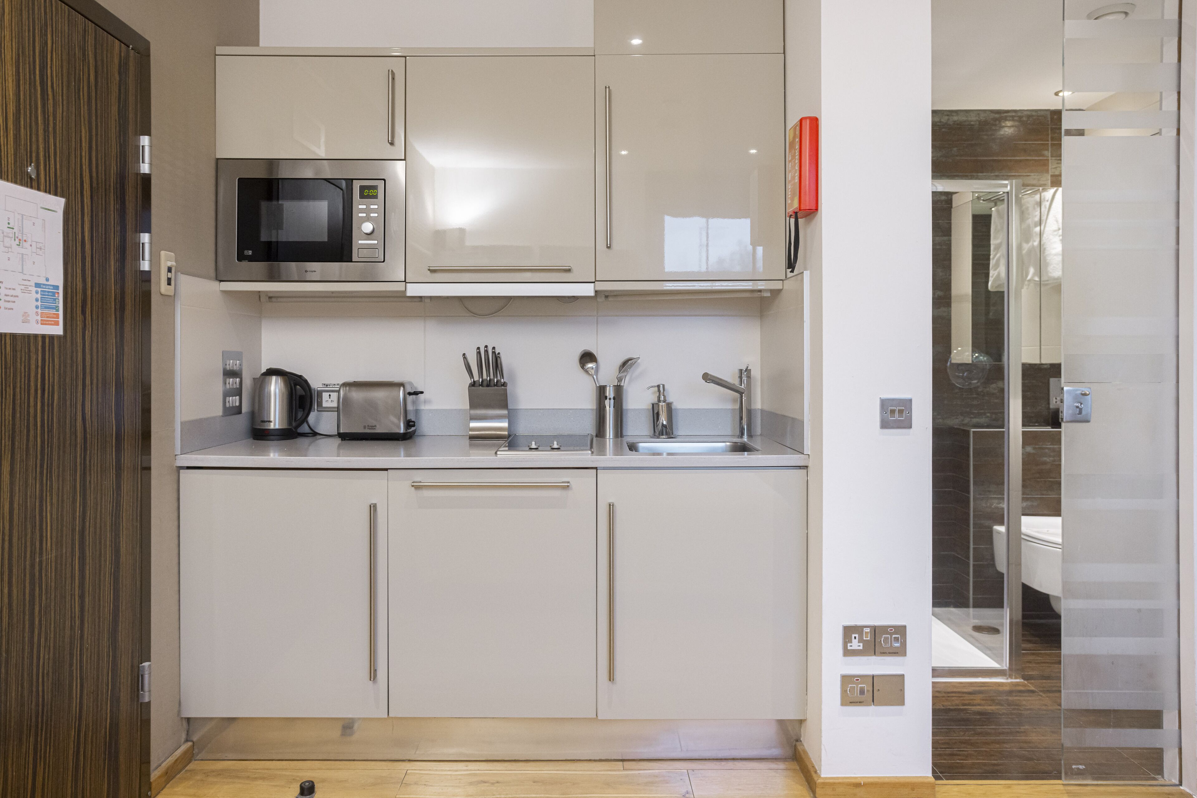 A modern kitchen with white cabinets, a microwave, a toaster, and a sink.
