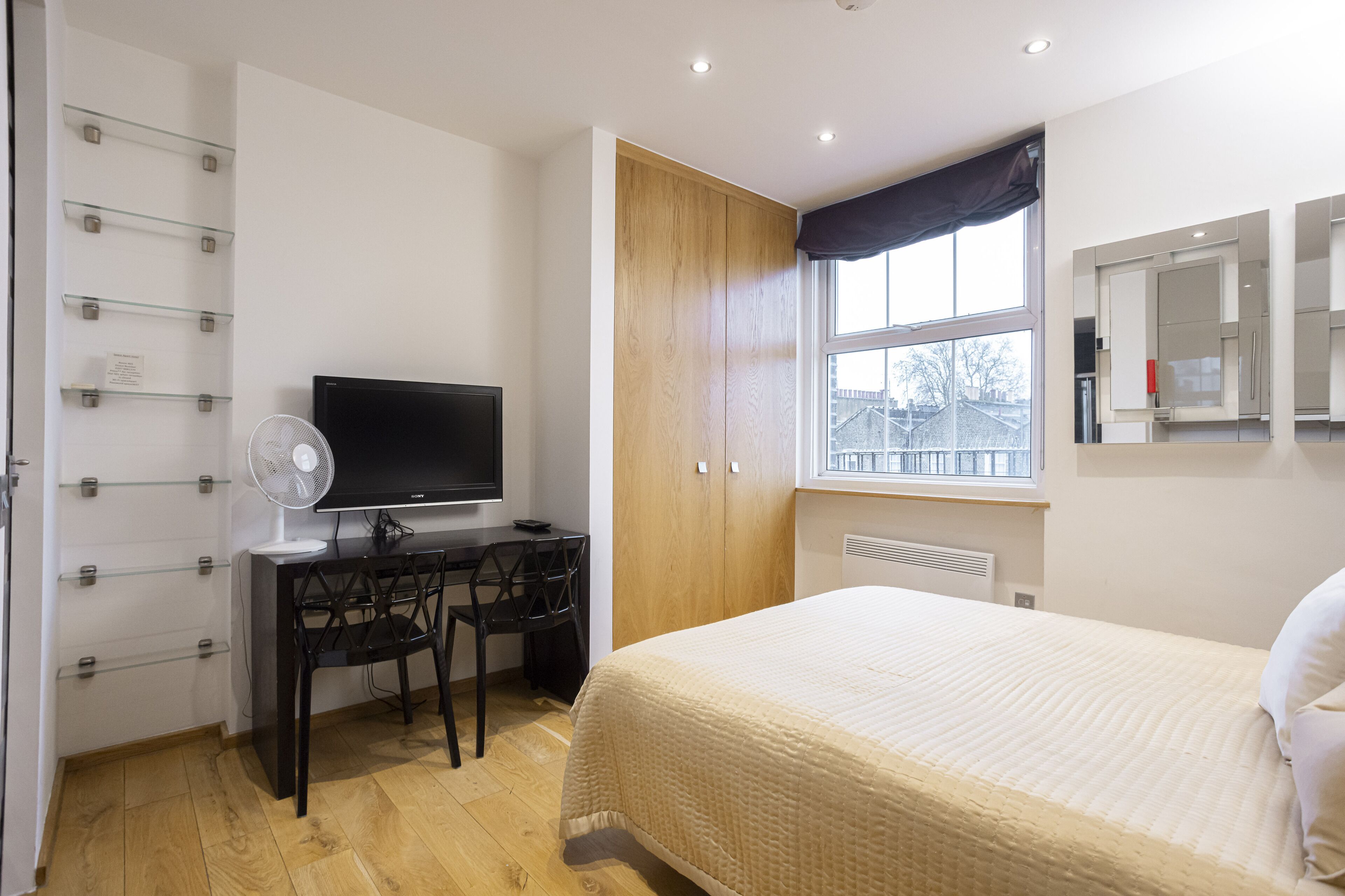 Una camera da letto con un letto, una scrivania con una sedia, una TV e una finestra con vista.