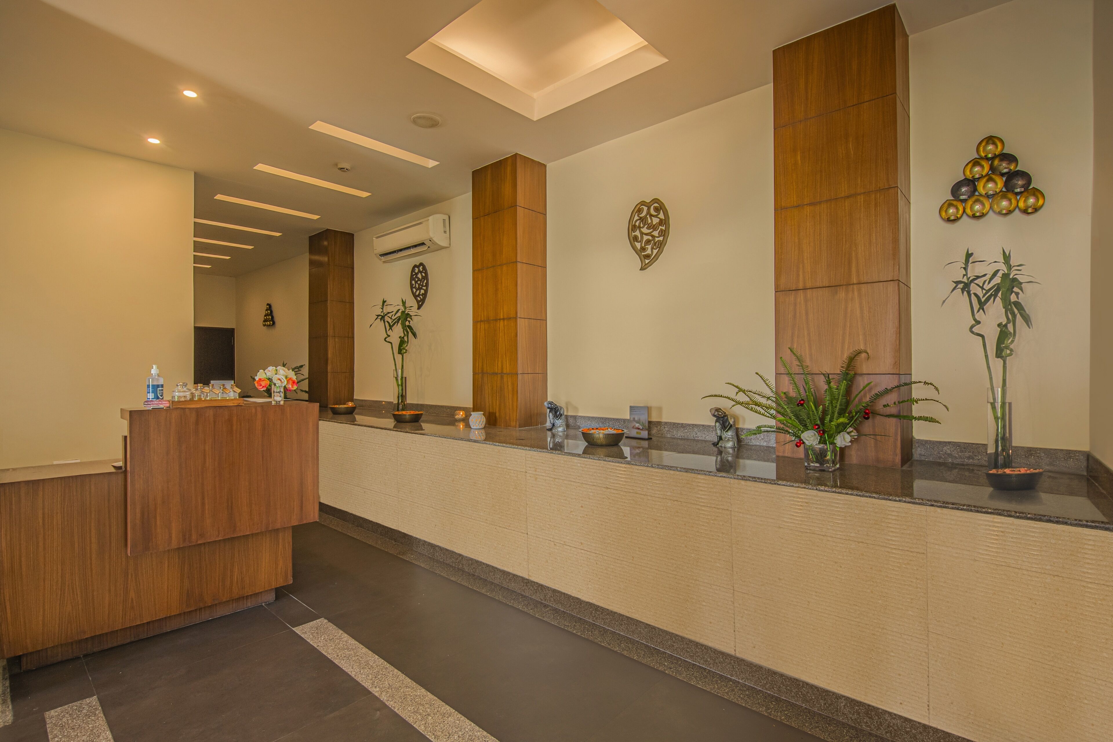 A reception area with a wooden reception desk, potted plants, and decorative wall art.