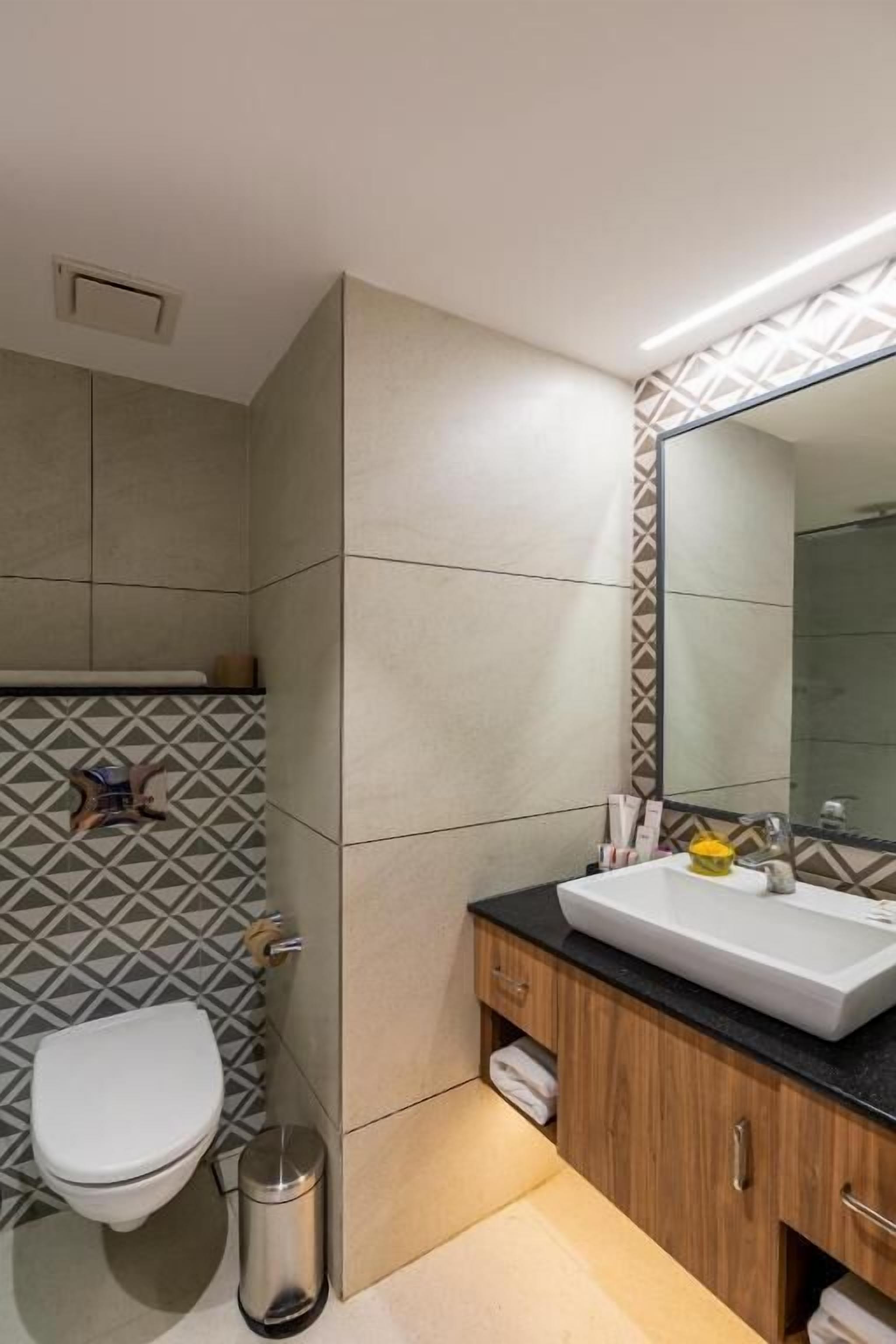 Une salle de bain moderne équipée de toilettes, d’un lavabo et d’un miroir.
