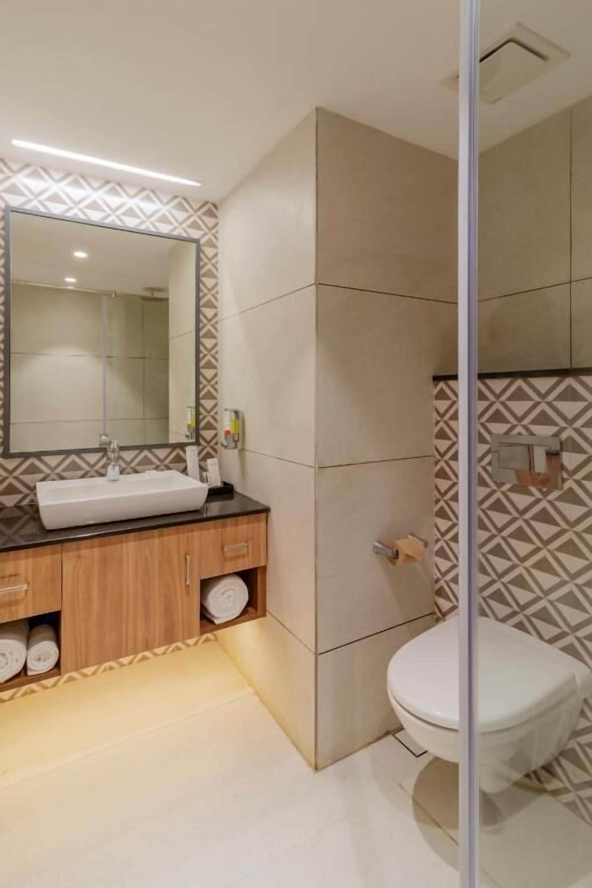 Ein modernes Badezimmer mit einem Holzwaschtisch, einem großen Spiegel und einer Toilette.