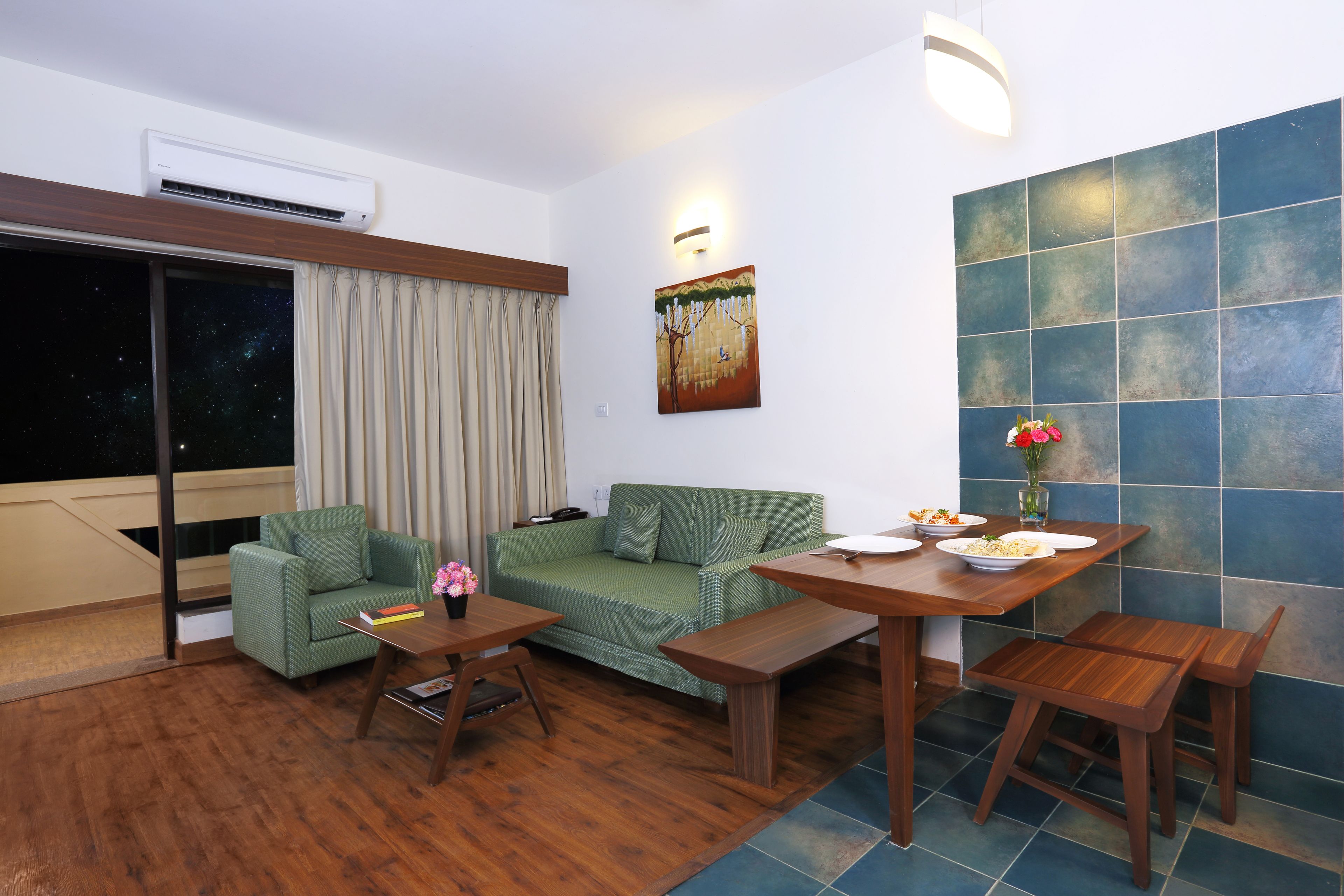 Een moderne woonkamer met een groene bank, een houten salontafel en een eettafel met stoelen.