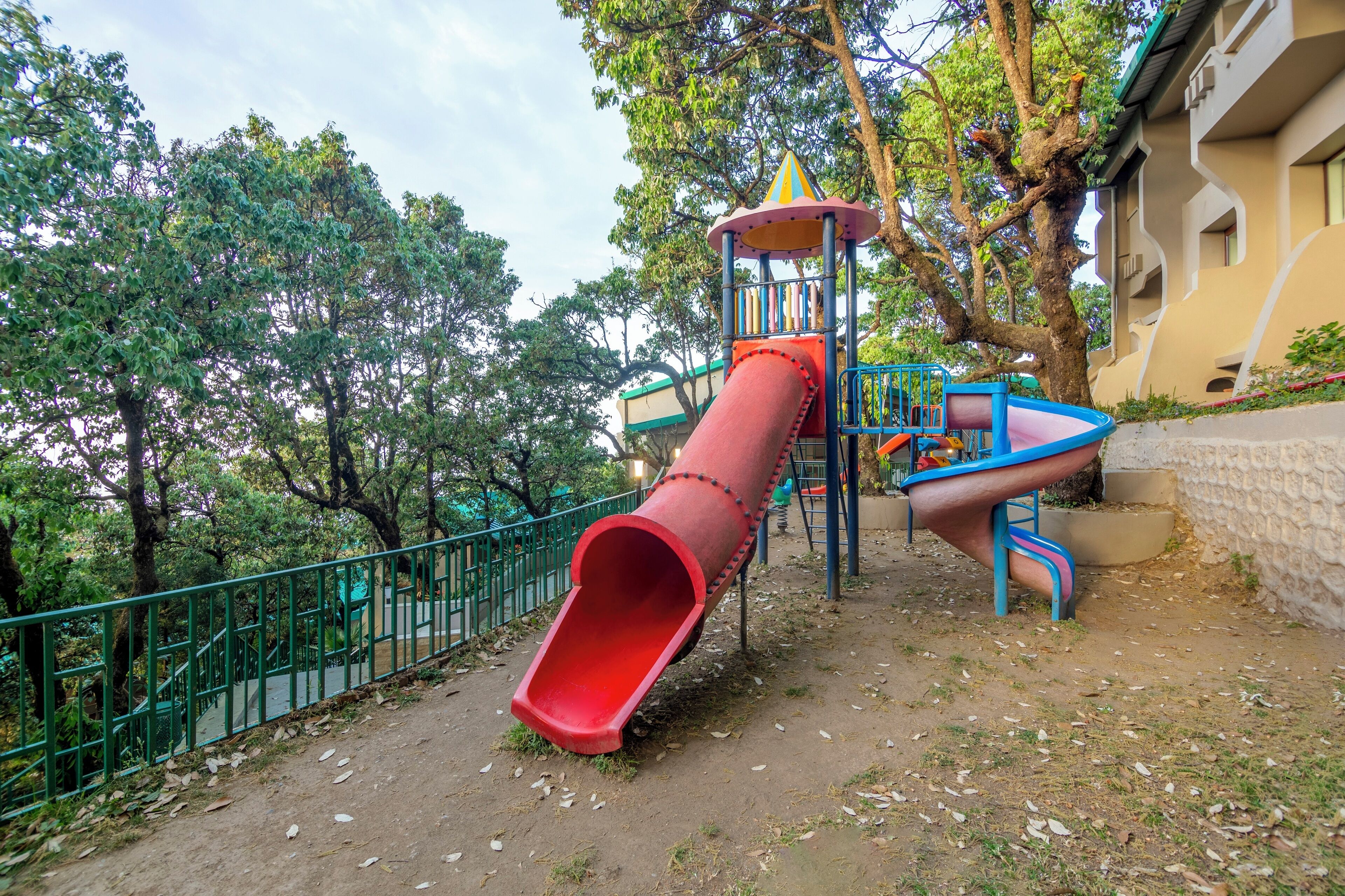 A playground with a red slide, a blue slide, and a climbing structure.