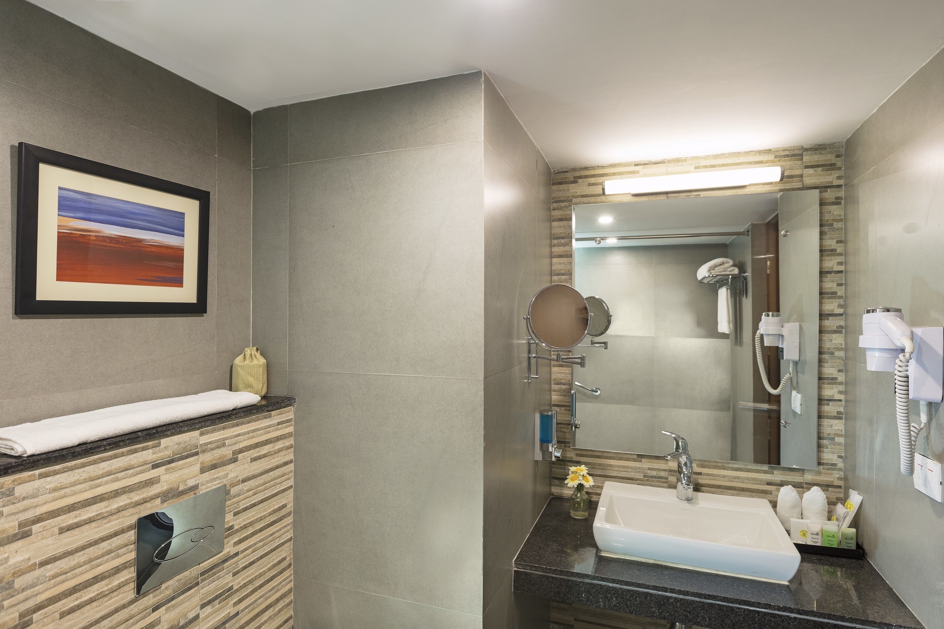 A modern bathroom with a large mirror, a sink, and a towel rack.