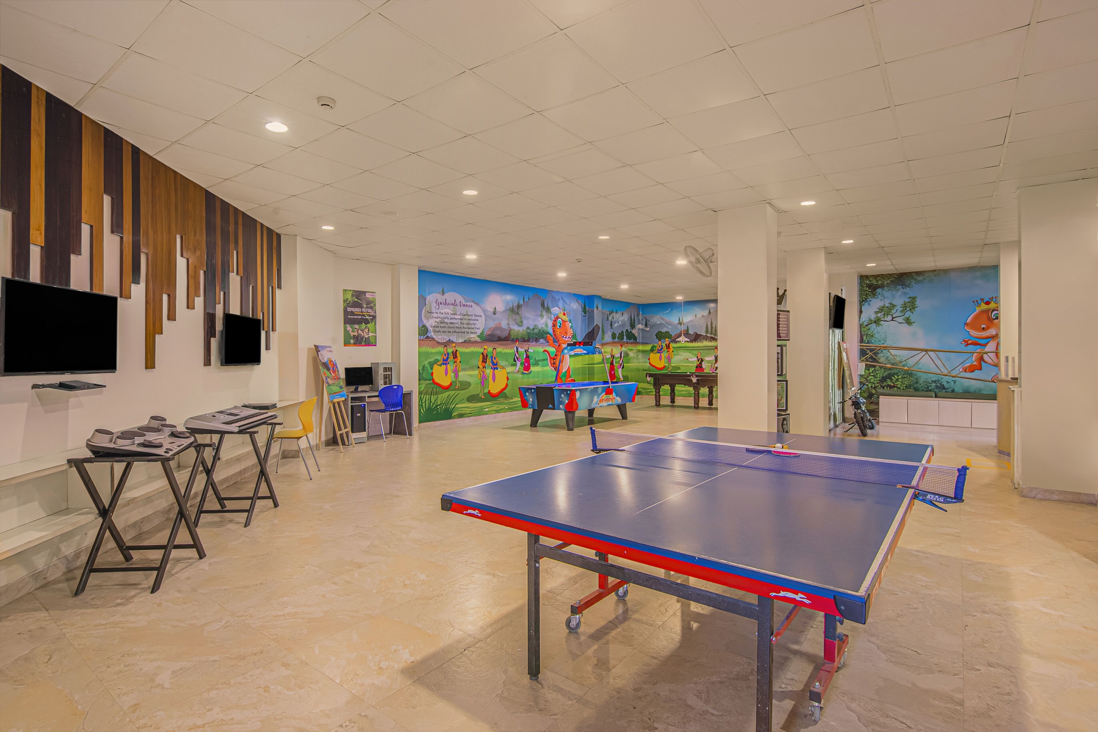 A spacious indoor area with a ping pong table, chairs, and a mural on the wall.
