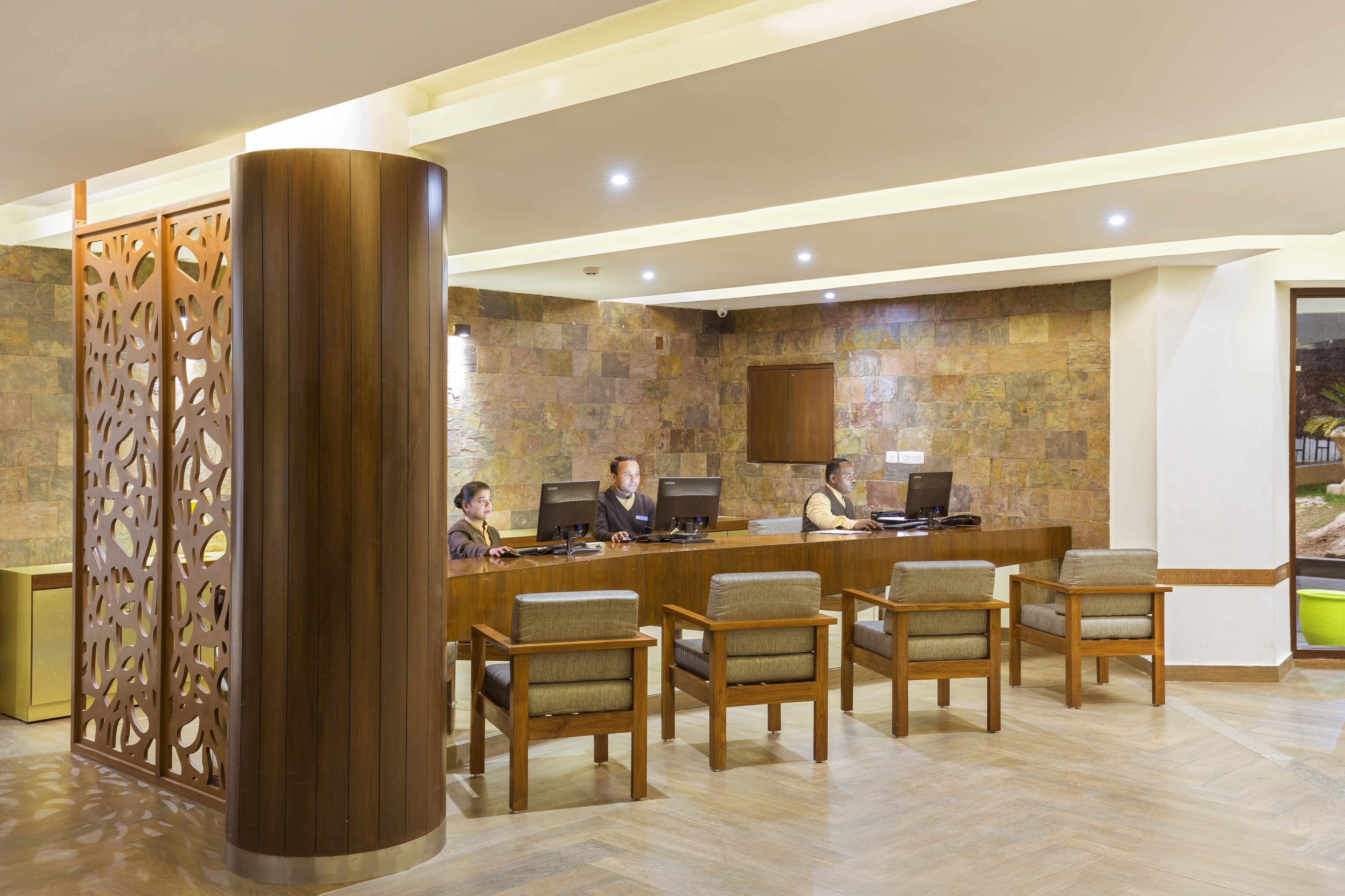 Uma área de recepção com balcão de madeira, várias cadeiras e um painel decorativo.