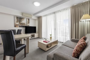 Une chambre d’hôtel moderne équipée d’un téléviseur à écran plat, d’une table à manger, d’un canapé et d’une table basse.