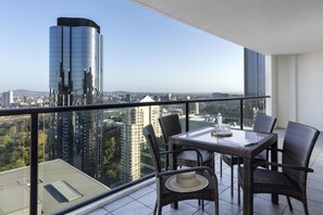 Un balcon avec une table et des chaises, donnant sur un paysage urbain avec des bâtiments modernes.
