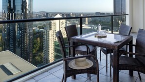 Un balcon avec une table et des chaises, offrant une vue sur la ville.