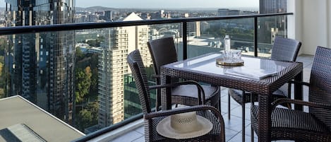 Un balcón con mesa y sillas, con vista a la ciudad.