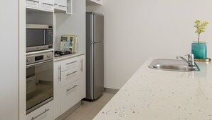 Une cuisine moderne avec des meubles blancs, des appareils en acier inoxydable et un plan de travail coloré à motifs.