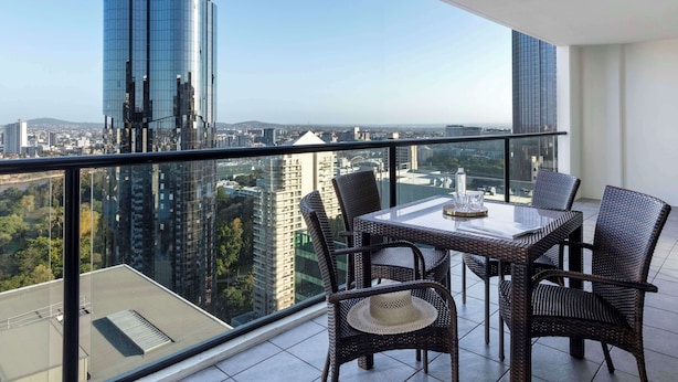 Un balcon avec une table et des chaises, donnant sur un paysage urbain avec des bâtiments modernes.