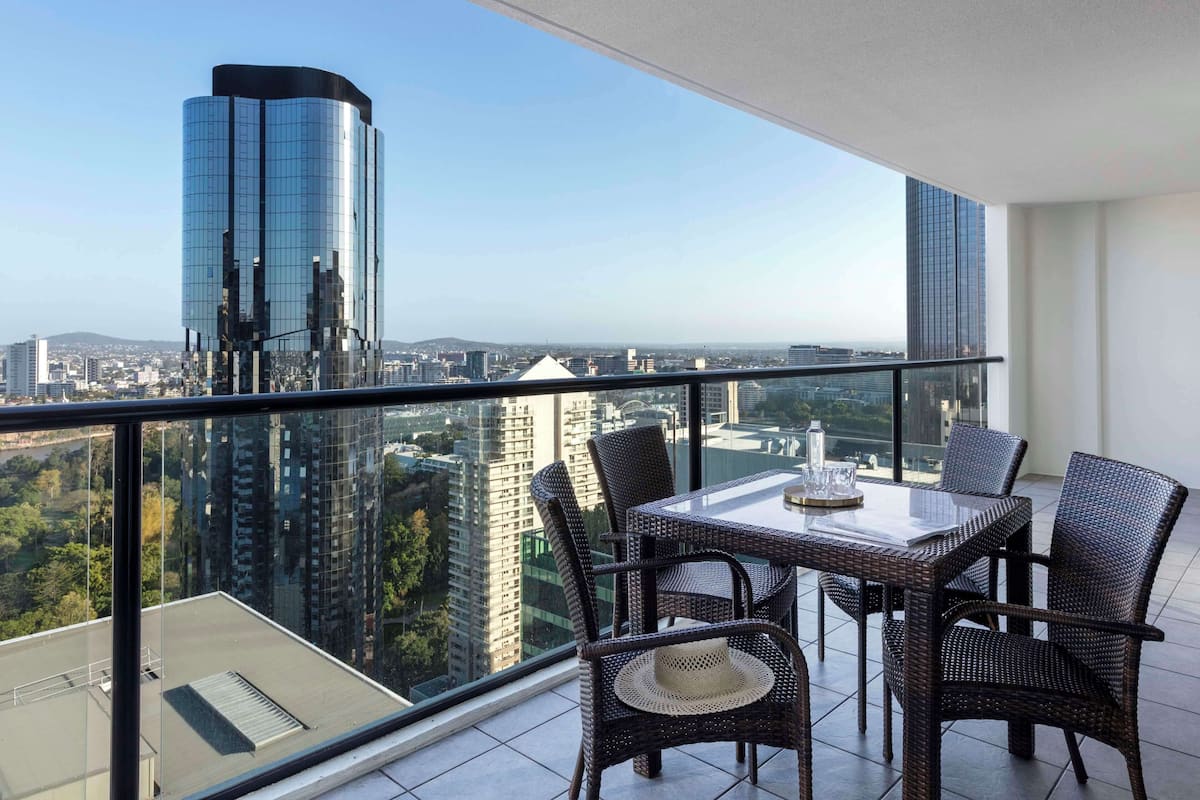 Ein Balkon mit Tisch und Stühlen mit Blick auf eine Skyline moderner Gebäude.