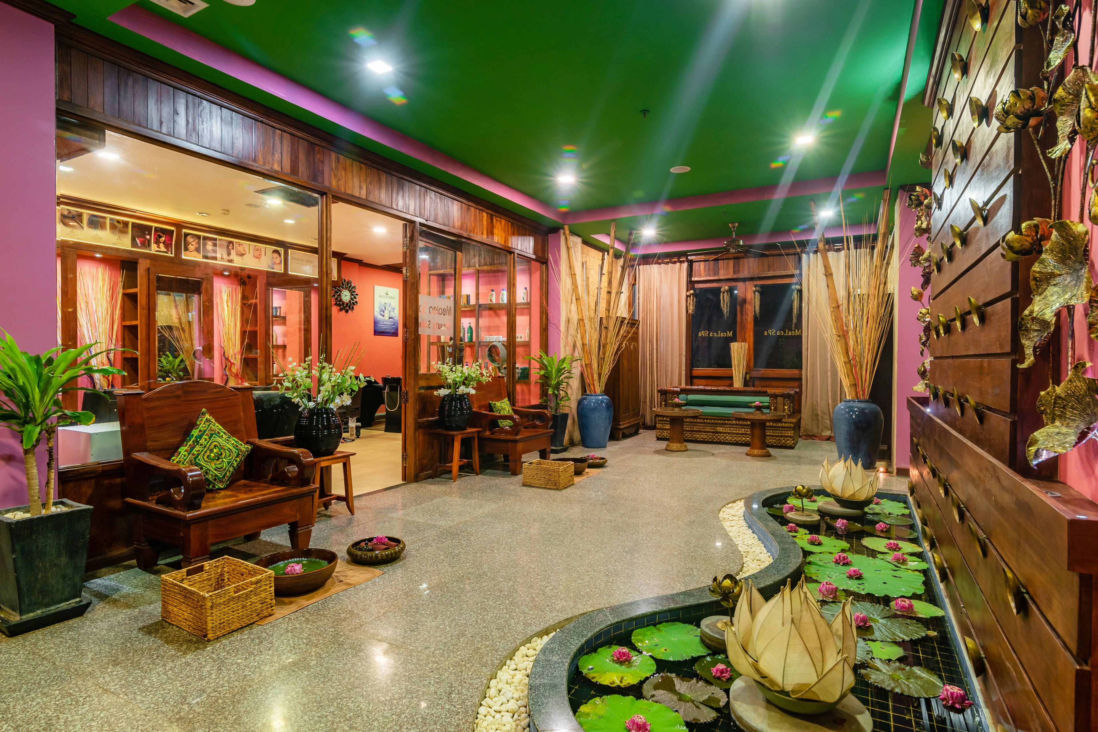 A traditional interior with a reception area, wooden furniture, a small pond with lotus flowers, and decorative wall elements.