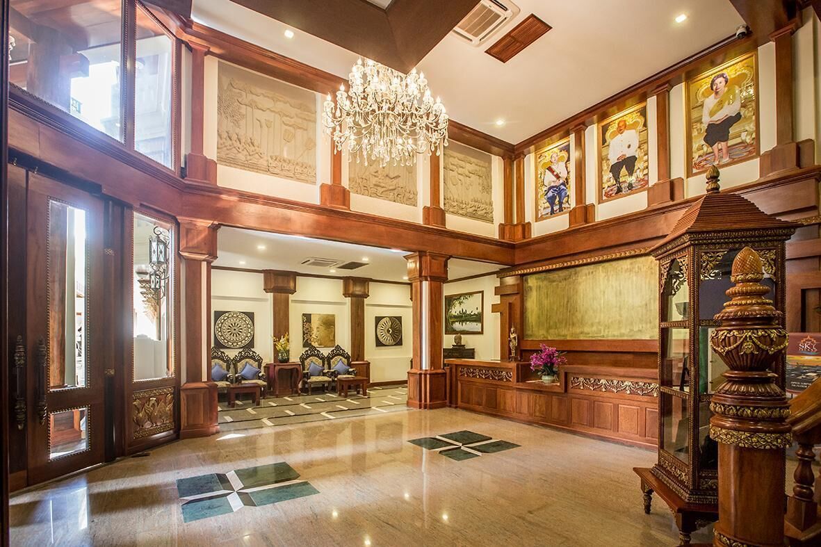 A grand lobby with high ceilings, chandeliers, and ornate woodwork.