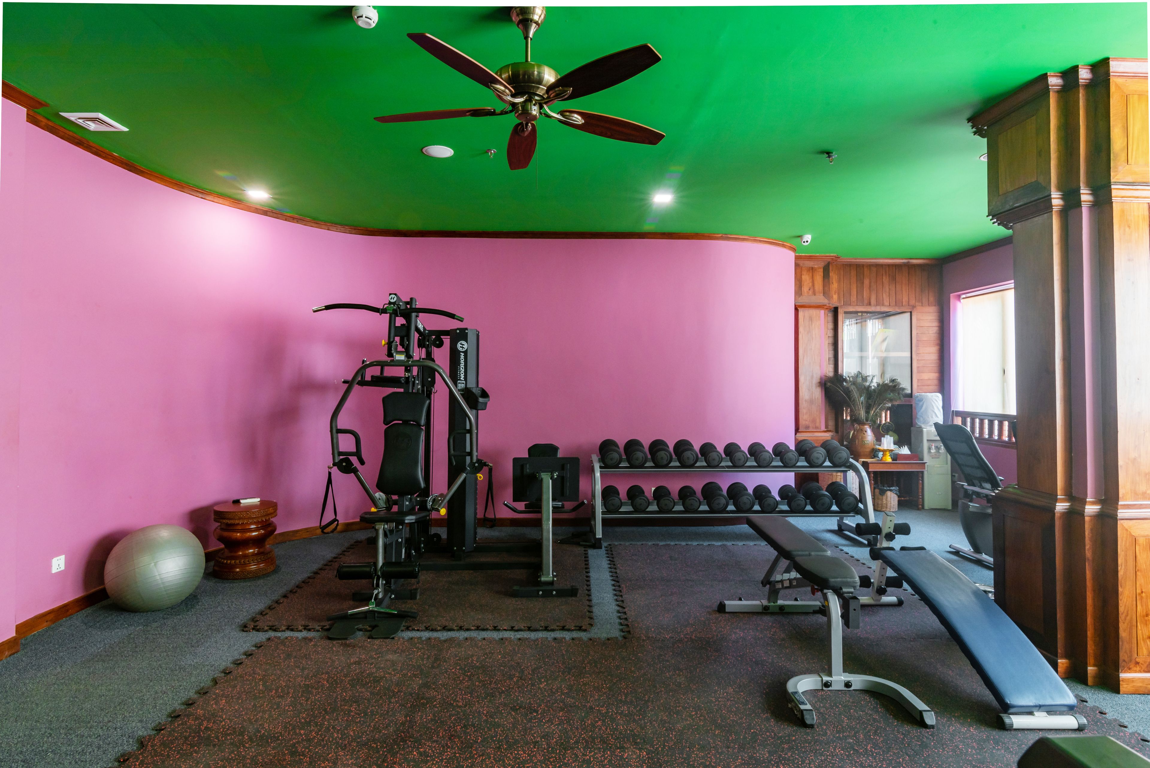 A gym with exercise equipment, a bench, and a rack of dumbbells.
