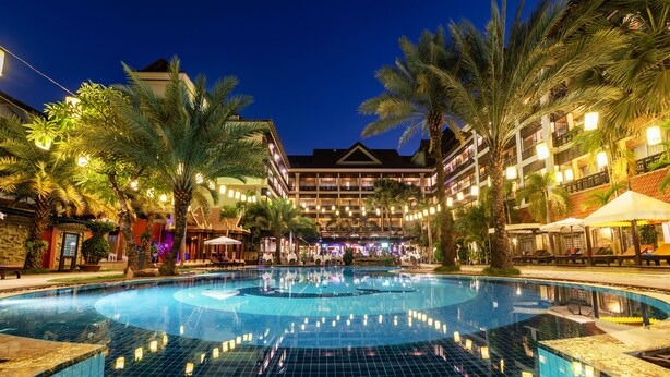 A swimming pool with a tiled deck, surrounded by palm trees and a building with multiple balconies. - Empress Angkor Resort & Spa (Siem Reap)