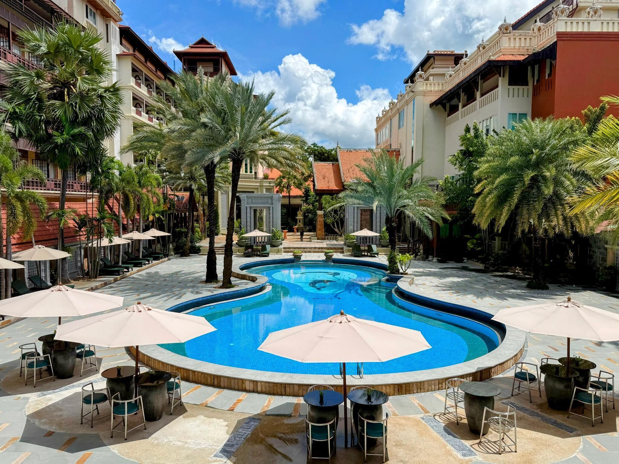 A pool area with a circular pool, lounge chairs, and umbrellas.