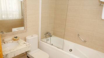 A bathroom with a marble sink, toilet, and a bathtub with a glass door.