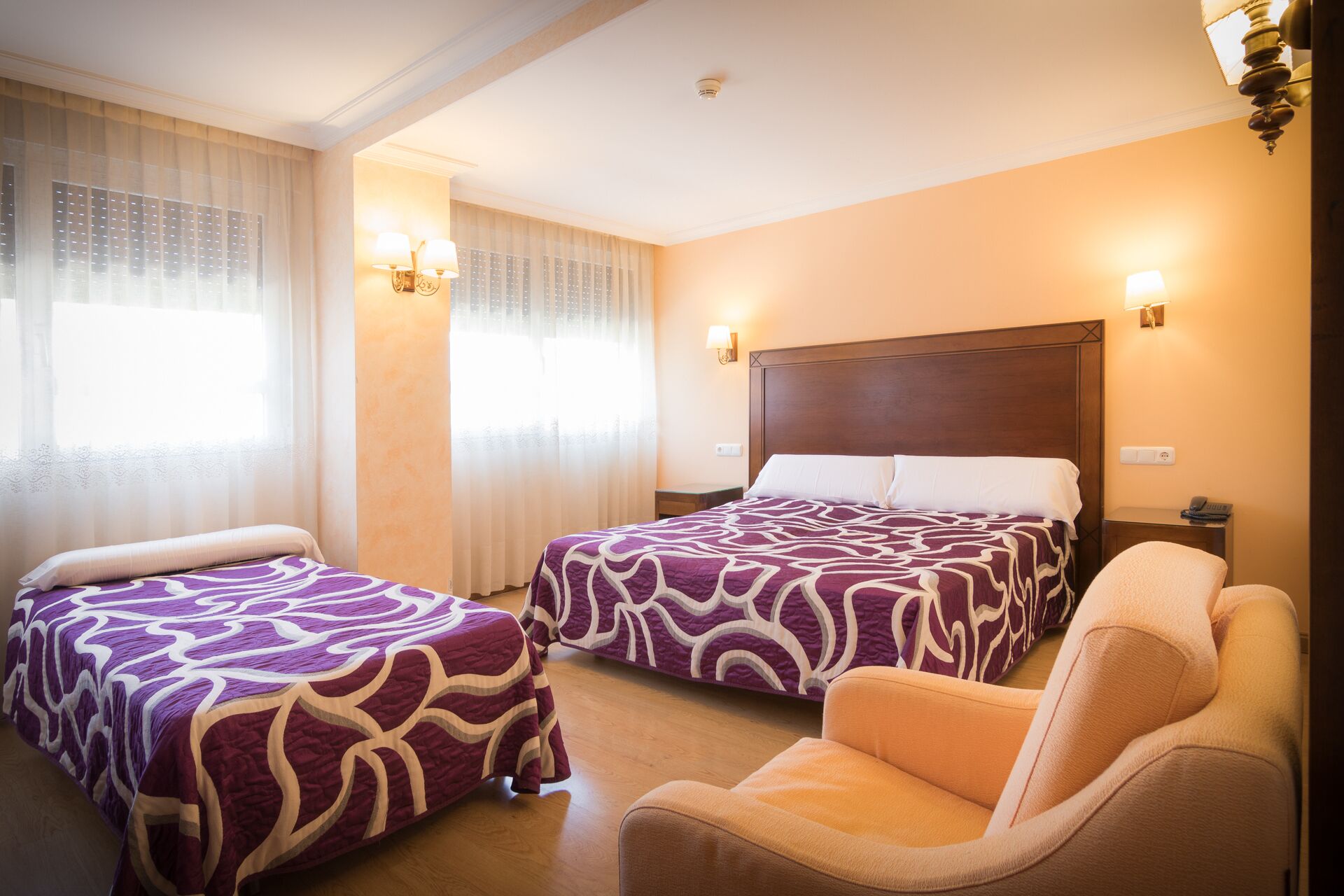 Habitación de hotel con dos camas, un sofá y una mesita de noche.