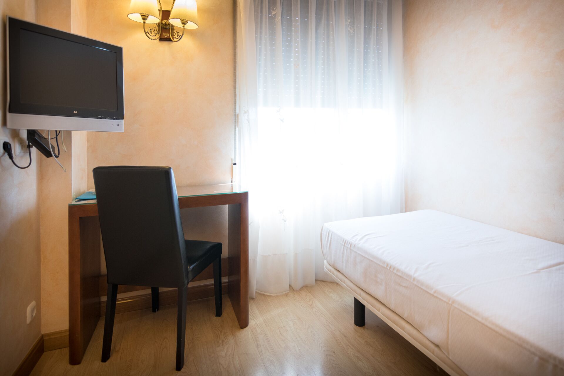 A small room with a bed, a desk, and a TV.