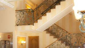 Un hall espacioso con una imponente escalera, asientos cómodos y un techo decorativo.
