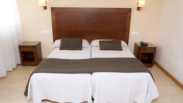 A double bed with a wooden headboard, two bedside tables, and two wall-mounted lamps.