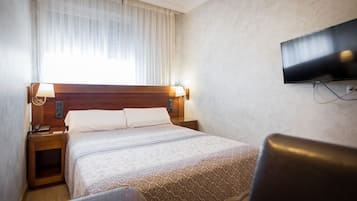 Una habitación de hotel con cama, mesitas de noche, televisión y una silla.