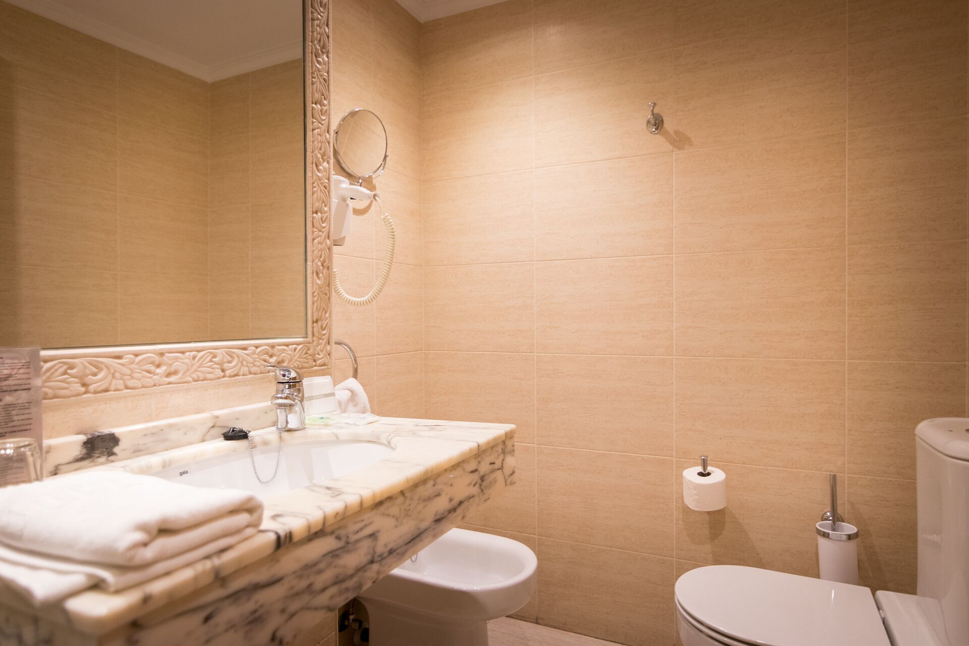 Un baño con lavamanos de mármol, inodoro y bidé.